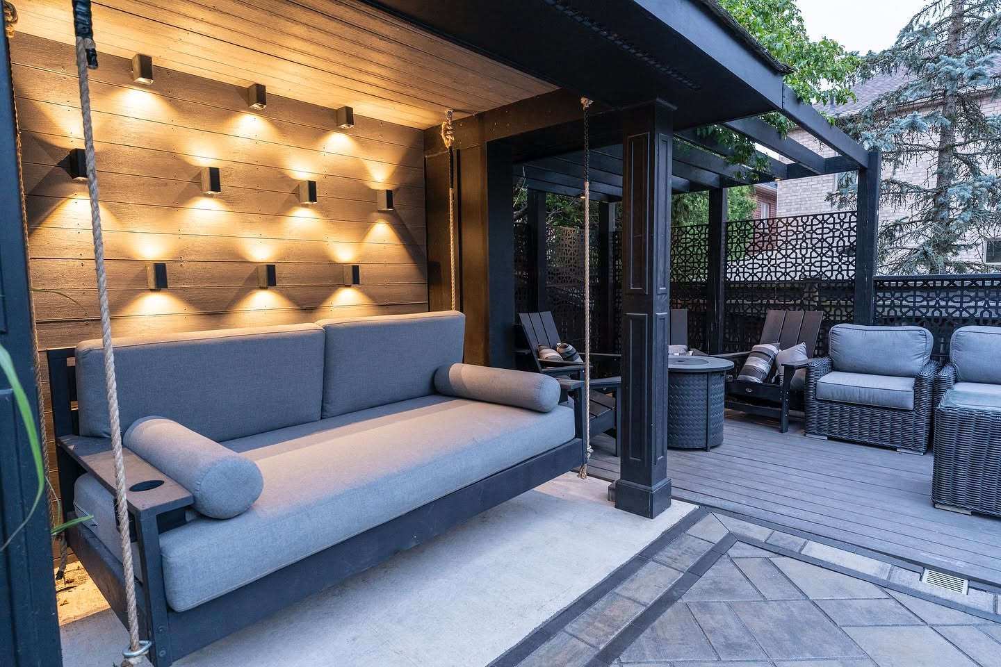 Custom black pavilion with hanging swing bed, wall lighting and decorative privacy screens