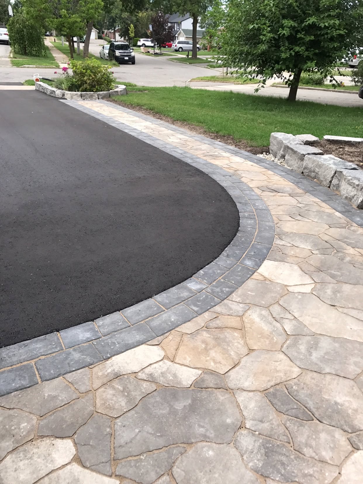 Asphalt driveway with flagstone paver border and armour stone garden edging
